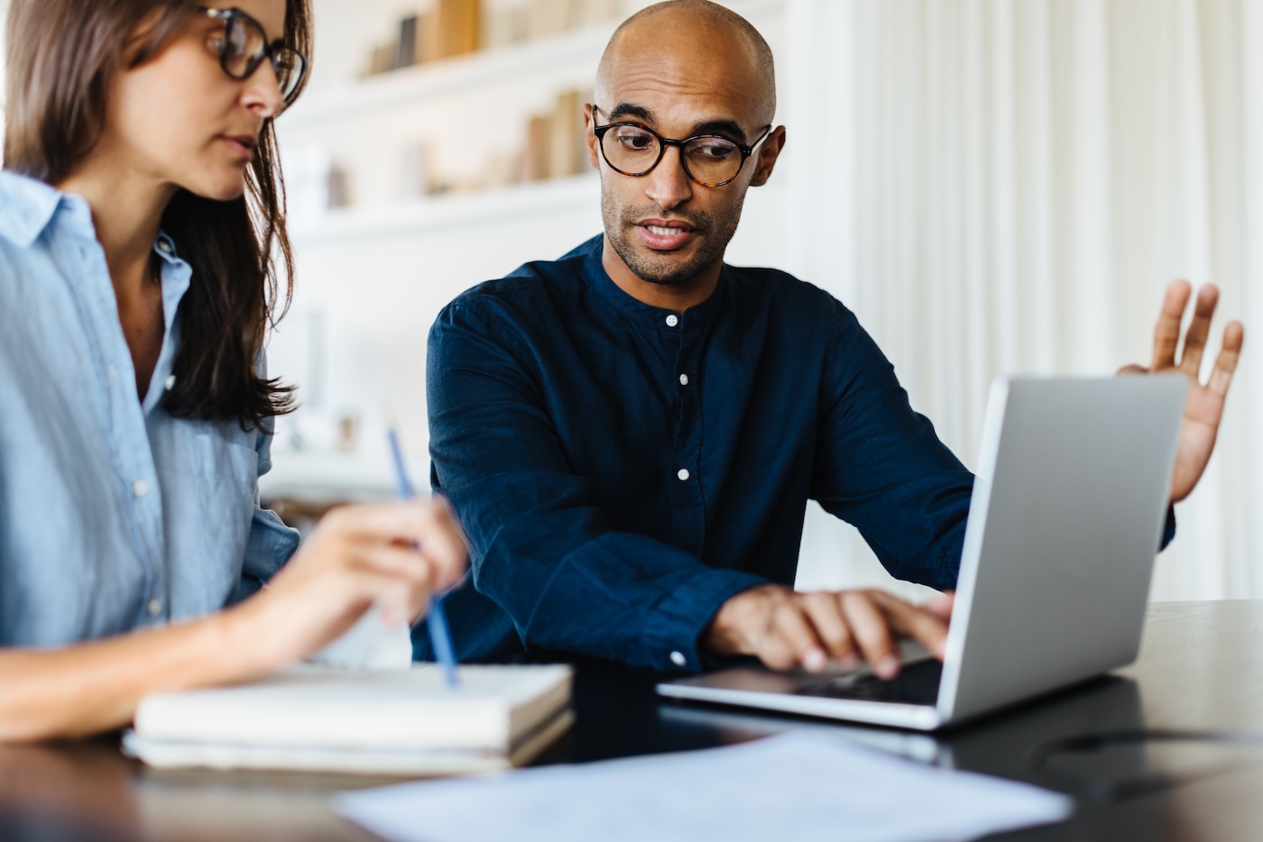 Business man using a laptop and discussing with his colleague in an office. Black business man having a meeting with a female professional.